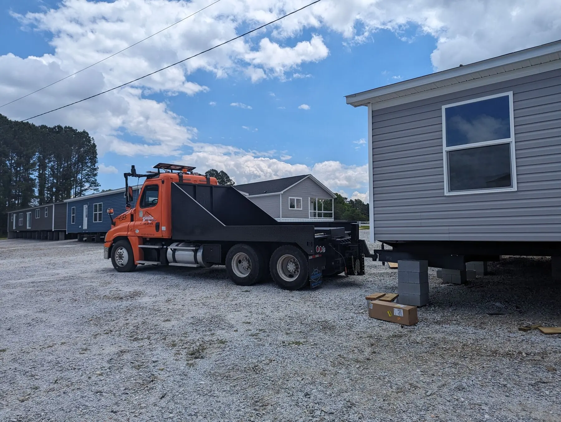 Orange truck transporting manufactured home.
